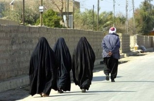 Arabic women walk behind a man.